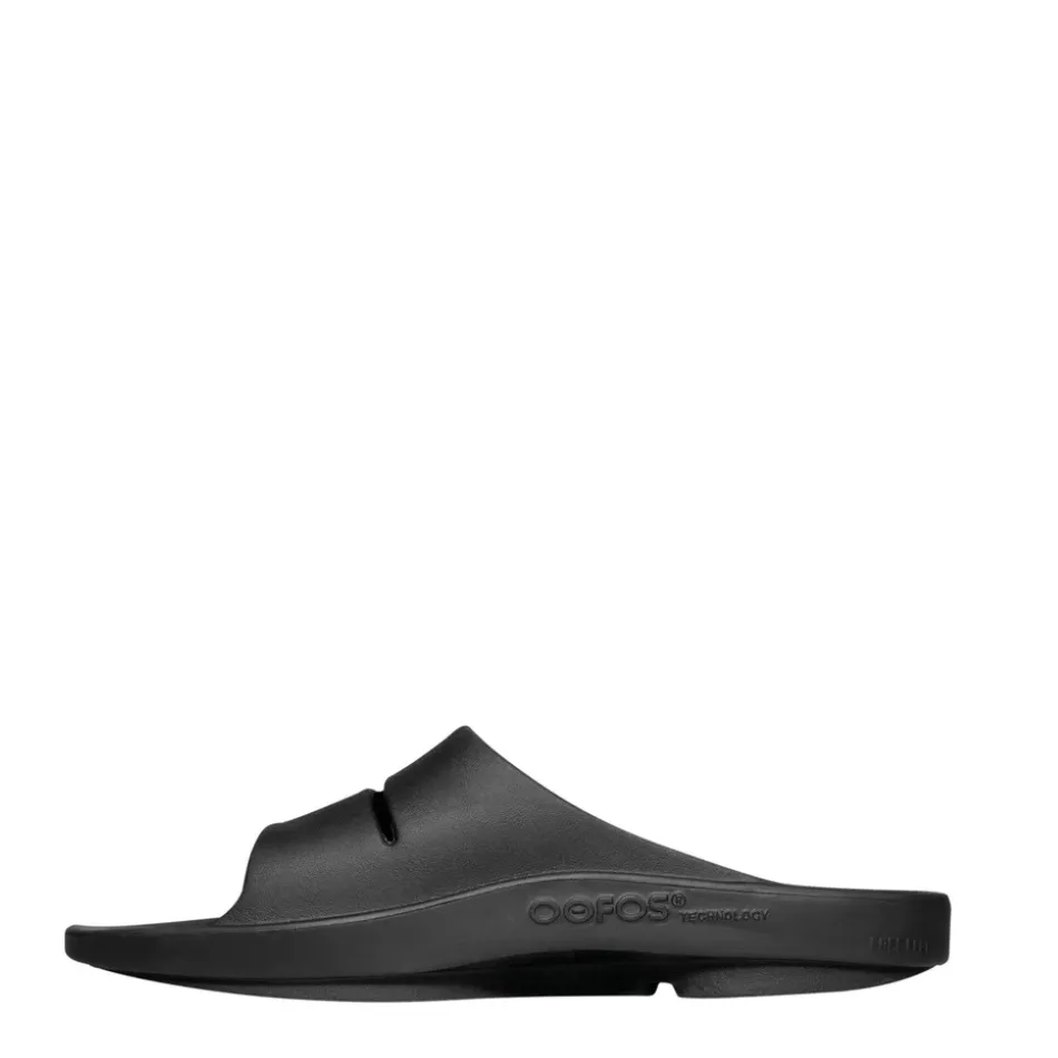 OOFOS OOahh Slide Sandal in Black running in a forest Reinforced Eyelet Durability